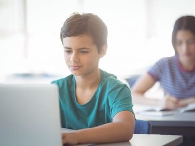 schoolboy-using-laptop-in-classroom-8DBV46T